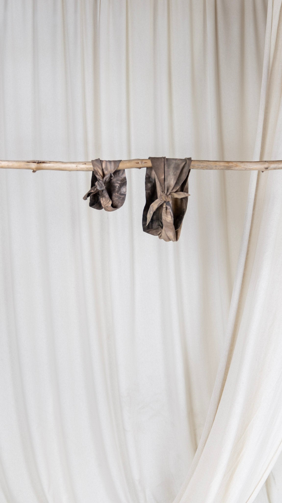 Two brown and purple colored jersey headbands folded and hanging on a piece of driftwood