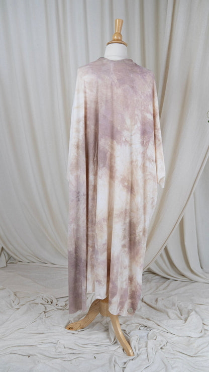 One light pink and white shawl hangs from a bust in front of a white curtain with the back facing the camera.