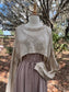 Mannequin wearing a beige top and brown dress against a natural background with trees.