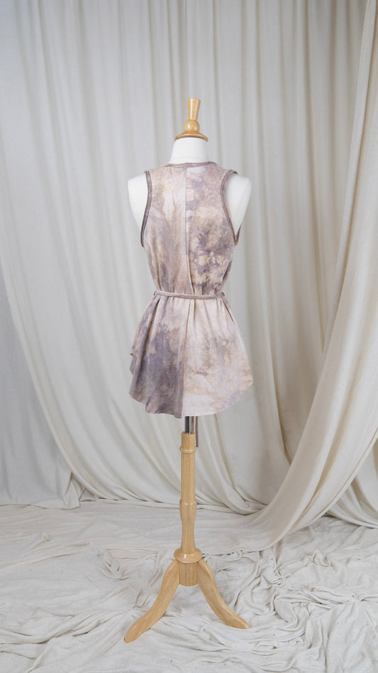 one light rose colored tank top with a scoop neck and a belted waist hangs from a bust with the back facing the camera.