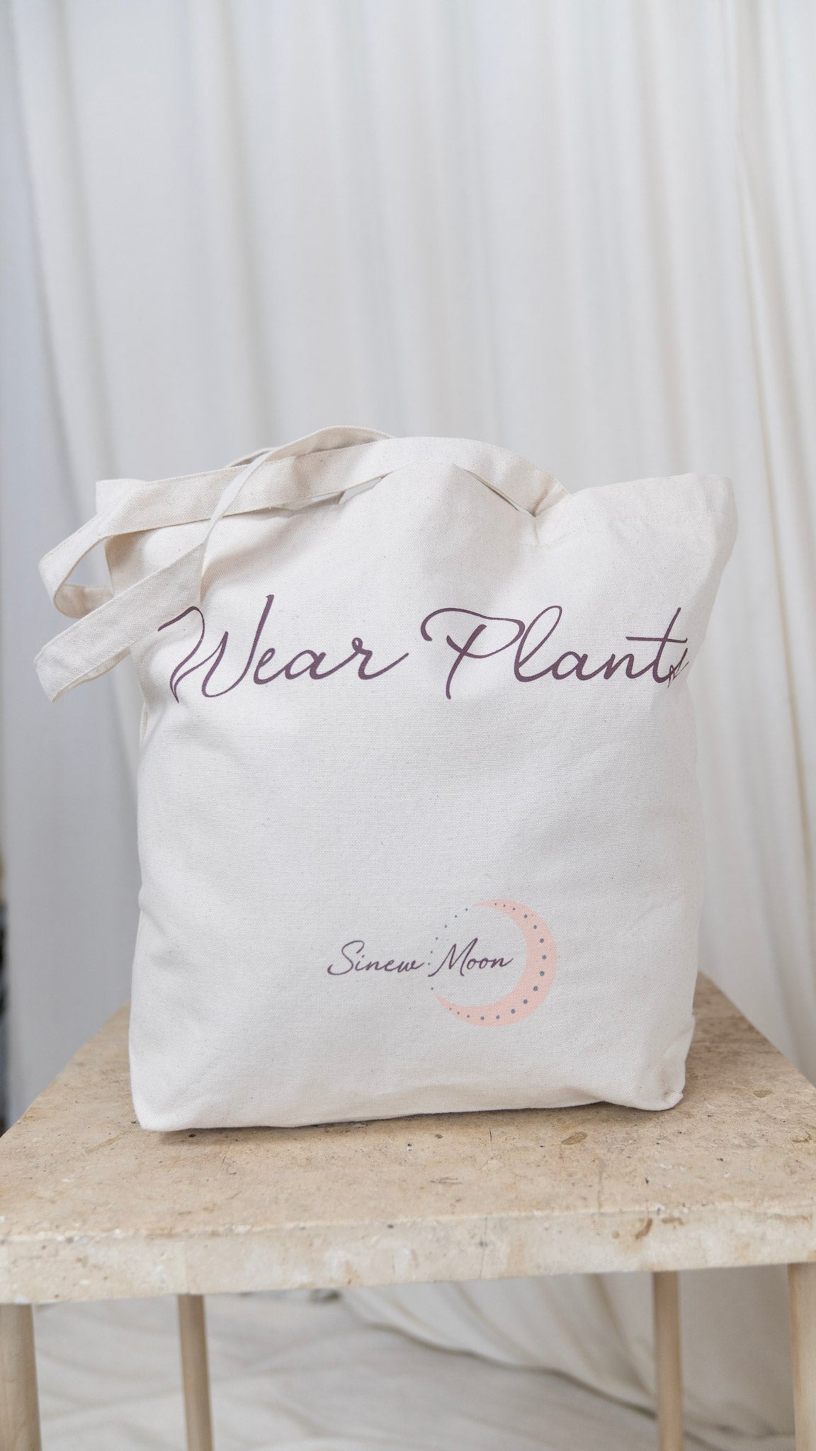 close up of one canvas tote with the words wear plants on the front