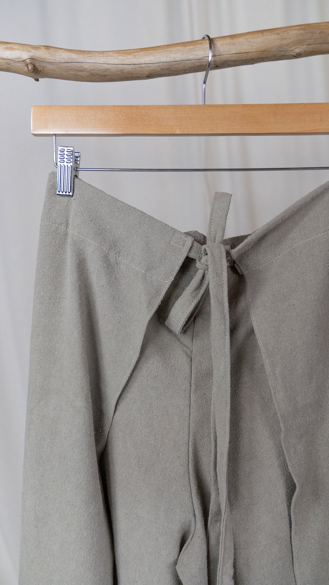 Closeup of greenish grey raw silk wrap pants and their tie feature