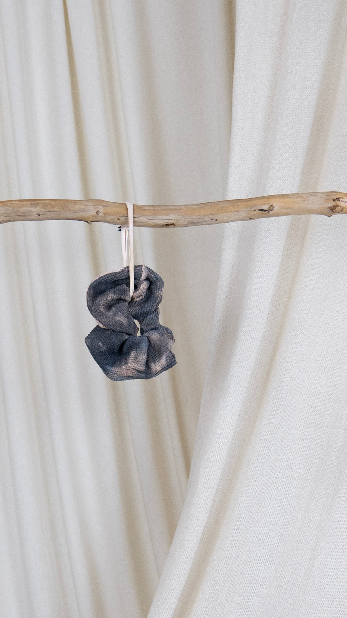 One dark and light purple dyed oversized thermal scrunchie hanging from a piece of driftwood