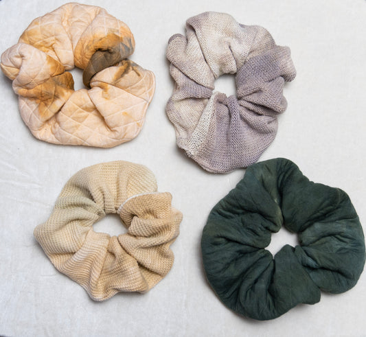 An overhead view of several oversized scrunchies in various colors on a white background