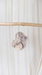 One light purple and cream dyed oversized sweater knit scrunchie hanging from a piece of driftwood