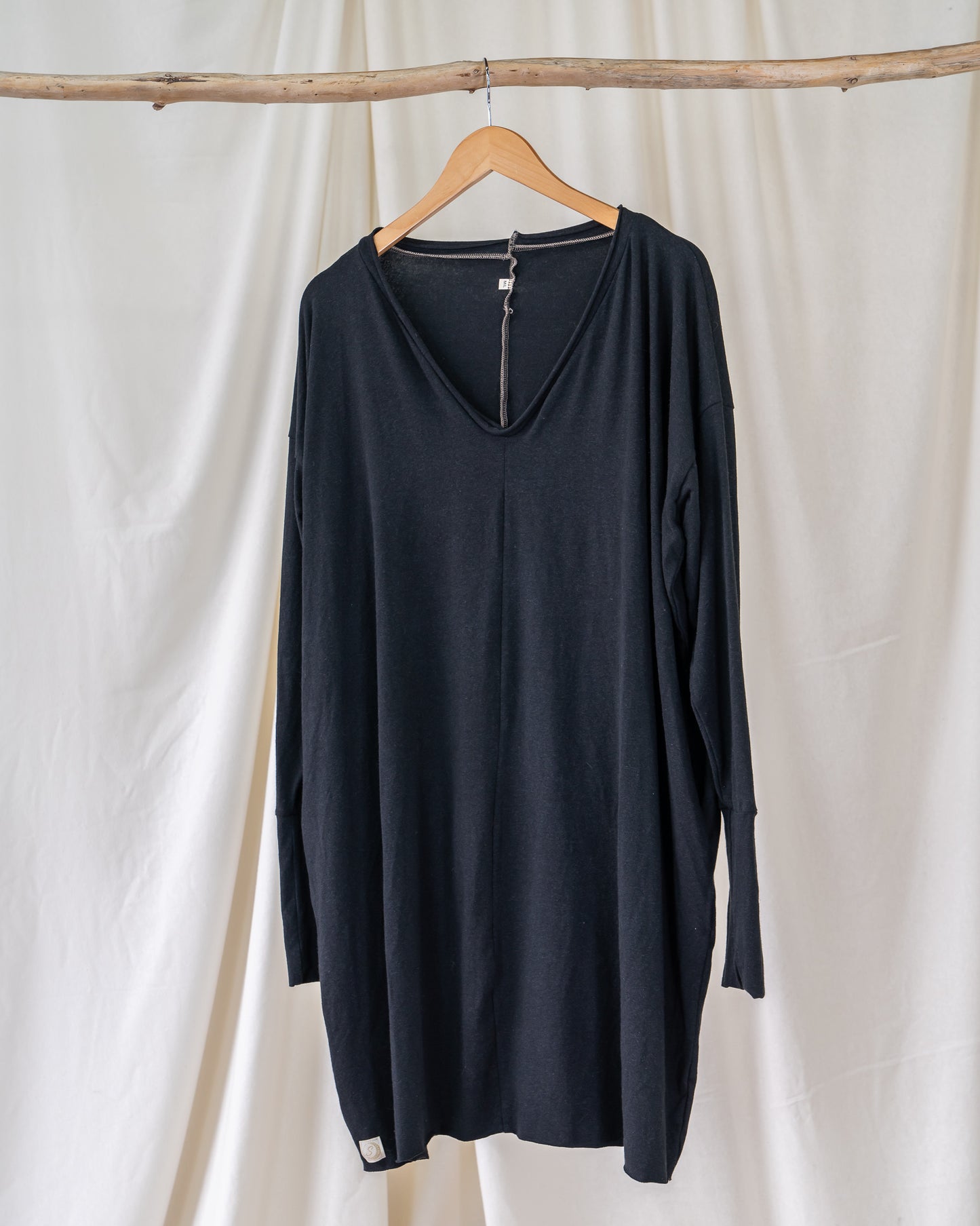 single black long sleeve shirt dress hanging on driftwood branch